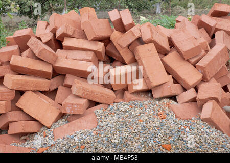 Viele rote Ziegel liegen auf dem Kies Stockfoto