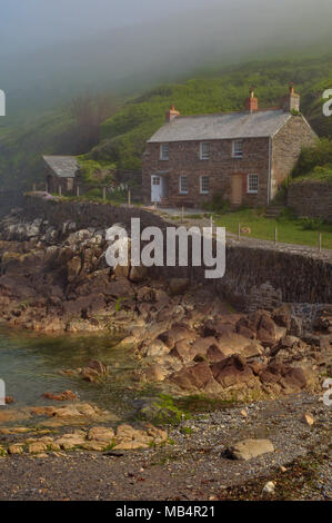 Eine wunderschöne alte Cornish Coastal Ferienhaus in einem kleinen Fischerdorf Bucht auf der Mantel in Cornwall. malerische Landhaus aus Stein auf der felsigen Küste misty gebaut. Stockfoto