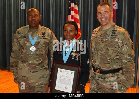 Sgt. Antasia Miller (Mitte) erhält eine Army Commendation Medal, Sergeant Audie Murphy Award, Medaillons und Münze von Command Sgt. Maj. John Johnson (links) und Brig. Gen. Sean Bernabe (rechts), Task Force Marne Team, während ein Sergeant Audie Murphy Induktion Zeremonie, 24.02.15, am Fort Stewart, Ga. in jedem der drei eingezogenen eine erforderliche Armee körperliche Fitness Test, schriftlicher und Praktischer Test und mündliche Board vor ihrer Aufnahme in den Club. Stockfoto