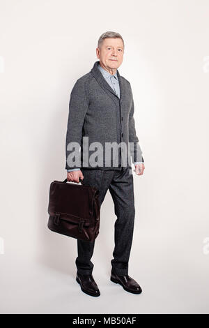 Im mittleren Alter Business Mann mit einem braunen Leder Aktentasche mit einem Laptop. Reifen Geschäftsmann Stockfoto