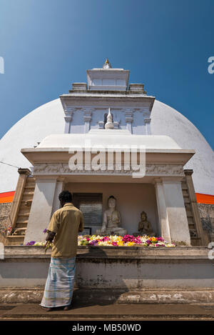 Vertikale Ansicht von einem Mann Blumen an ruwanwelisaya Dagoba oder Stupa in Anuradhapura, Sri Lanka. Stockfoto