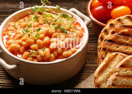 Bohnen in Tomatensoße und Toast auf hölzernen Hintergrund Stockfoto