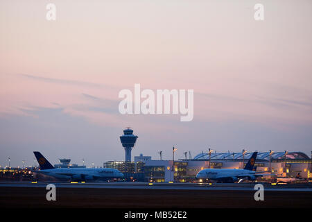 Zwei Lufthansa Airbus Flugzeuge, A380-800, vor Terminal 2 mit Turm, Dämmerung, Flughafen München, Oberbayern, Bayern Stockfoto