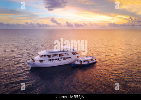 Diving Safari Schiff MS Keana mit tauchdhoni bei Sonnenuntergang verankert, Ari Atoll, Malediven, Indischer Ozean Stockfoto