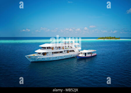 Diving Safari Schiff MS Keana mit tauchdhoni aus verankert eine unbewohnte Palm Island, Ari Atoll, Malediven, Indischer Ozean Stockfoto