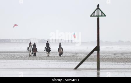 Reiter machen sich auf den Weg entlang der West Wittering Strand in West Sussex. Stockfoto