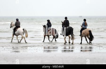 Reiter machen sich auf den Weg entlang der West Wittering Strand in West Sussex. Stockfoto