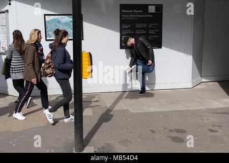 Ein Mann nimmt vorsichtig etwas von der Sohle von seinem Schuh, an der Ecke der Bach und New Bond Street, am 6. April 2018 in London, England. Stockfoto