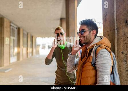 Zwei junge Männer sprechen über das Telefon in der City passage Stockfoto