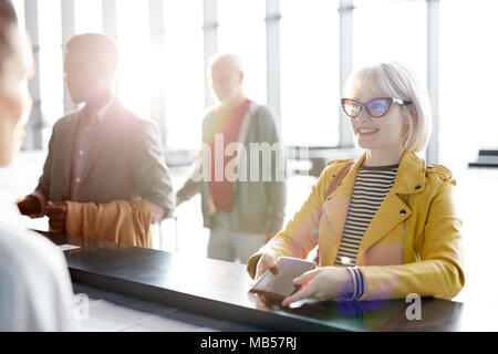 Hübsche Blondine mit Reisepass suchen bei der Registrierung Manager bei Check-in-Schalter vor dem Flug Stockfoto