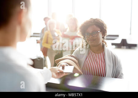 Registrierung manager Geben zurück Pass zu einem der Reisende nach dem Check-in Vor dem Flug Stockfoto