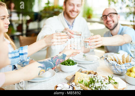 Gesellschaft von Freunden Toasten mit Gläsern frischen hausgemachten Limonade über serviert Tabelle während der festlichen Abendessen Stockfoto