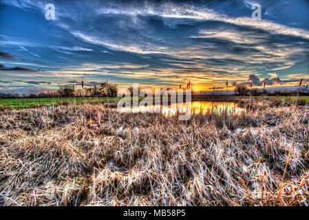 Dorf von Coddington, England. Künstlerische Sonnenuntergang Blick auf ein Süßwasser-Teich in einem Cheshire Landwirtschaft Feld. Stockfoto