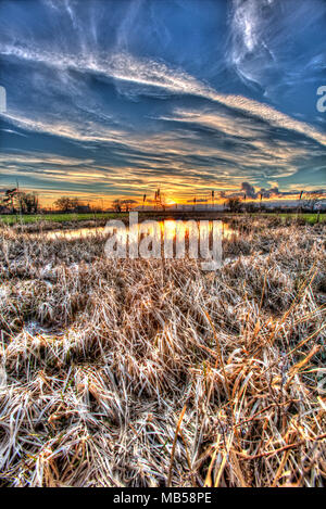 Dorf von Coddington, England. Künstlerische Sonnenuntergang Blick auf ein Süßwasser-Teich in einem Cheshire Landwirtschaft Feld. Stockfoto