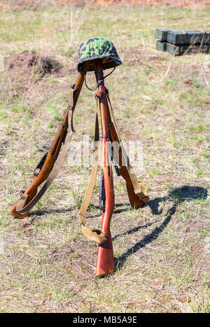 Vintage russischen militärischen Gewehre (mosin System, Modell von 1938) und Deutschen Helm auf dem Schlachtfeld Stockfoto