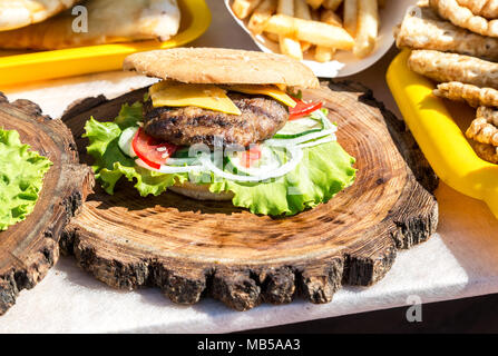 Leckere Burger mit Hähnchenfleisch, Käse und frischem Gemüse auf Holzbrett. Einfache Idee für vegetarisches Sandwich Stockfoto