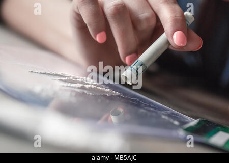 Junge weibliche Droge soziale Probleme am Tisch sitzen Sniffing heroin Makro Nahaufnahme durch dollar Banknote süchtig Stockfoto