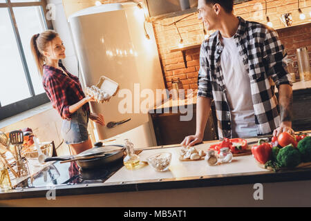 Frau mit viele Eier für Abendessen und schlägt Mann. Kochen zu Hause. Innen-, Studio shot Stockfoto