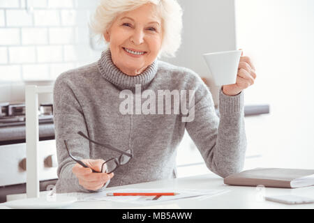 Glück alte Frau in der Küche trinken Kaffee am Morgen. Innen-, Studio Shoot, Küche Innenraum Stockfoto