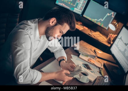 Junger bärtiger Mann Händler im Büro sitzen am Tisch zählen Geld holding Banknoten konzentriert Business Fonds Stockfoto
