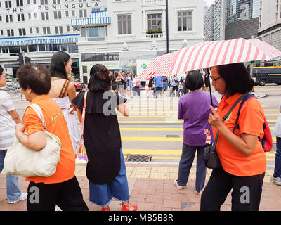 KOWLOON HONG KONG - 20. SEPTEMBER 2017; körnig Candid close-up Handy Bild Frauen im City Fußgängerzone eine Kreuzung mit gestreiften Schirm Stockfoto