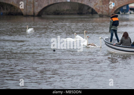 Familie in kleinen Motorboot mit Schwimmwesten und Kind trat auf Bogen mit Brücke im Hintergrund Stockfoto