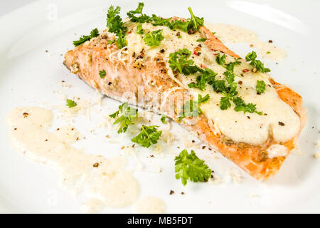 Gebratener Lachs mit Käsesoße, Petersilie und Pfeffer. Stockfoto