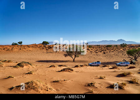 Zwei 4x4 Autos der Touristen selfdriving Fahrt durch die Dünen von einsame Wüstenlandschaft des NamibRand Nature Reserve, Namibia, Afrika Stockfoto