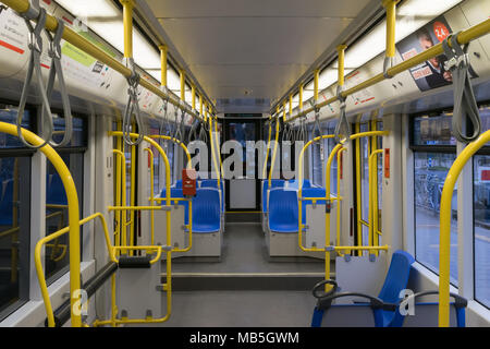 Straßenbahn innerhalb, City Transport Innenraum mit blauen Sitze in Reihe, gelb Griffe für stehende Fahrgäste, hellem Licht und Klimaanlage in Köln Stockfoto