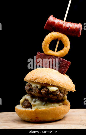 Eine doppelte Wildschwein Burger aus einem Wildschwein geschossen in der Toskana, Italien, mit cambozola Käse und mit Chorizo Wurst und frittierten Zwiebeln garniert r Stockfoto