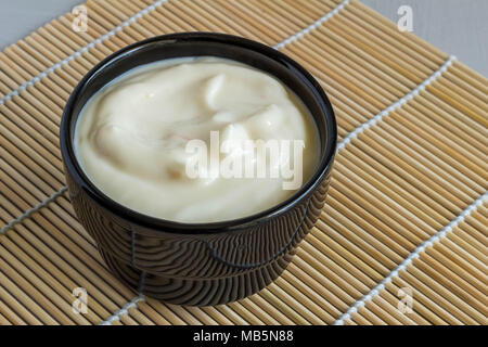 Cremige Frucht Joghurt in schwarz Schüssel auf Reed Tabelle mat Nahaufnahme Stockfoto