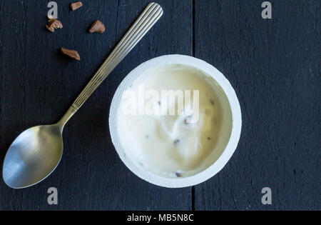 Joghurtbecher mit Vanille sahne Joghurt und choc Chips auf schwarzem Hintergrund Stockfoto