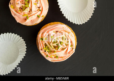 Zwei rosa cup cakes schließen bis auf schwarzem Hintergrund - Ansicht von oben Foto mit Platz für Text Stockfoto