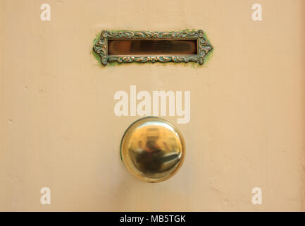 Altes Messing e-Mail Letter Box und Tür-Knopf auf eine gelbe Tür Stockfoto