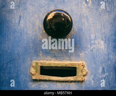 Altes Messing e-Mail Letter Box und schwarzen Tür Knopf auf einem blauen verwitterte Tür Stockfoto