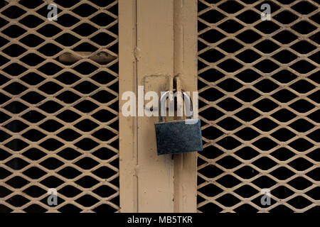 Tür verschlossen. Geschlossenes Vorhängeschloss auf einem alten gelben Metall, Detailansicht Stockfoto