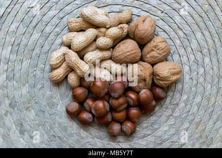 Erdnüsse, Haselnüsse und Walnüsse mit nußschalen Mix auf natürlichem Bambus matte Oberfläche Stockfoto