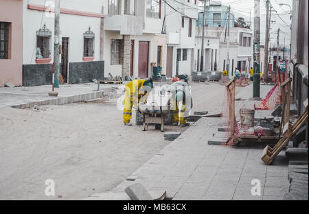 Regierung contracte Arbeiter in Gelb verglastes Gang & grün Schutzausrüstung Schutzhelme auf ebnet eine Straße mit Betonblöcken in Arequipa, Peru arbeiten Stockfoto