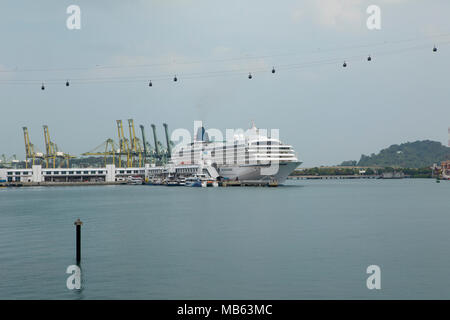 Kreuzfahrtschiff Asuka II besessen und durch Nippon Yusen Kaisha betrieben günstig in der Nähe der Insel Sentosa in Singapur. Die Insel Seilbahn vor der Kreuzung. Stockfoto