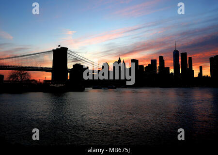Ein dramatischer Sonnenuntergang silheottes die Skyline über Manhattan, New York City, USA Stockfoto