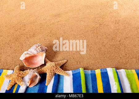 Beach border with towel, starfish and seashells.  Space for copy.  Sharp focus on the foreground objects.  Studio shot - directional lighting and warm Stockfoto