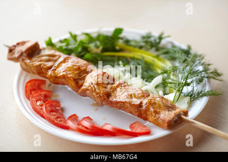 Gegrilltes Schweinefleisch Kebab am Spieß mit Tomaten, Zwiebeln und Grüns auf Platte Stockfoto