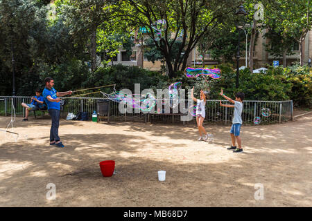 BARCELONA, Spanien, 6. Juli 2017: Nicht identifizierte Kinder spielen in Gaudi Platz mit Seifenblasen, die durch eine Straße. Stockfoto