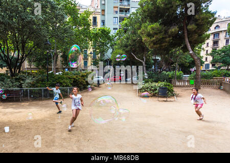 BARCELONA, Spanien, 6. Juli 2017: Nicht identifizierte Kinder spielen in Gaudi Platz mit Seifenblasen, die durch eine Straße. Stockfoto