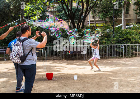 BARCELONA, Spanien, 6. Juli 2017: Unbekannter Tourist nimmt Fotos der Kinder spielen mit Seifenblasen von Street Artists in Gaudi Platz gemacht Stockfoto