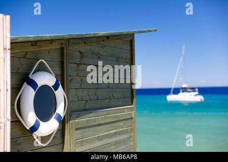 Szene Sommer mit einem Rettungsring auf einer hölzernen Hütte und ein Schiff im Hintergrund aufgehängt Stockfoto