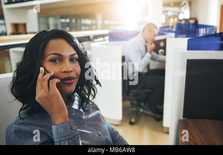 Junge hübsche Afro-amerikanische Frauen im Büro sitzen und in Gespräch mit Blick auf die Kamera. Stockfoto