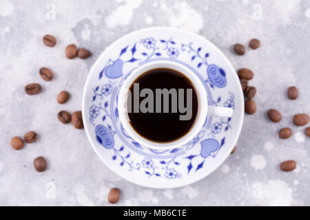 Ein schönes Porzellan Kaffee Tasse mit heißem Kaffee. Kaffeebohnen rund um den Hintergrund verstreut. Vintage China. Stockfoto