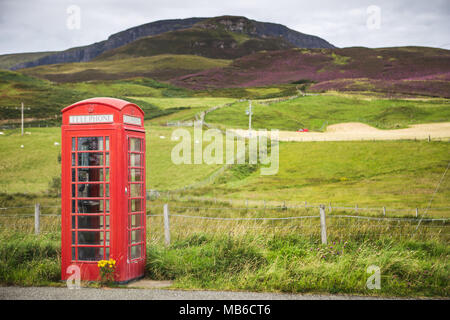 Traditionelles rotes Feld neben einer einzelnen Spur Straße der Insel Skye, Schottland Stockfoto