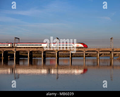 Ein Virgin Trains Westküste pendolino Zug in den Fluss Esk bei Mossband, nördlich von Carlisle auf der West Coast Main Line wider Stockfoto